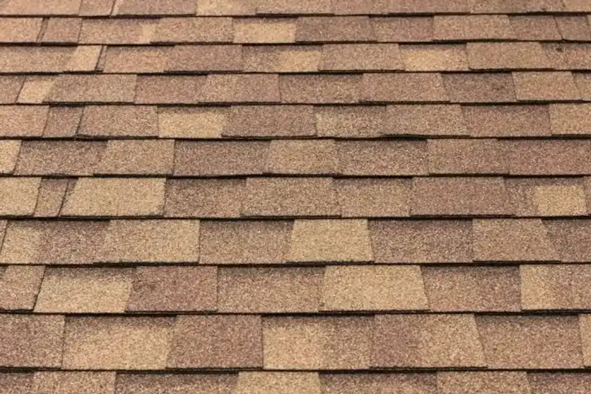 Close-up of brown architectural asphalt shingles showing their layered, dimensional pattern