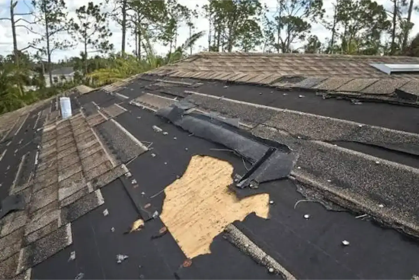 Shingle roof with missing shingles and a bare patch of decking, two common roof problems